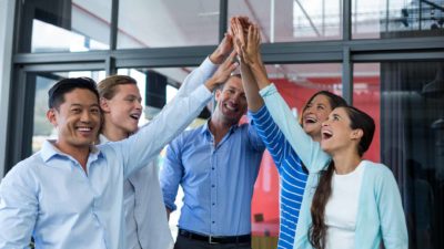 Five people in an office high five each other.