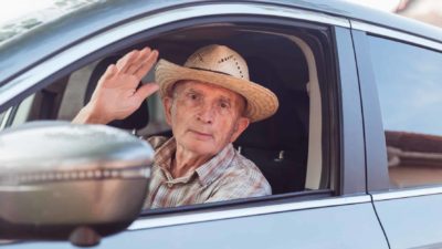 A sad traveller sitting in a car waves goodbye