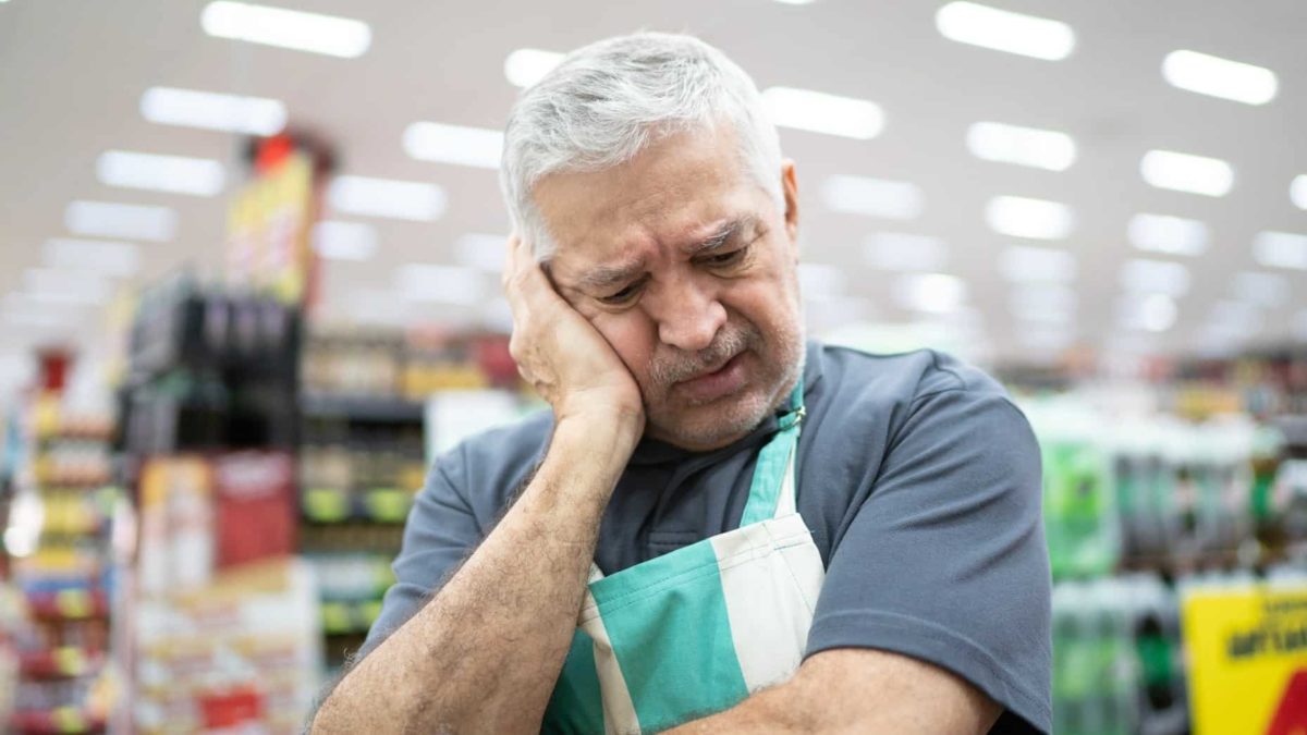 Supermarket worker looks upset.