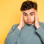 A worried man holds his head in his hands