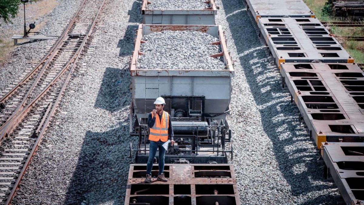 A worker in a hard hat reports an issue with the freight train on his walkie talkie.