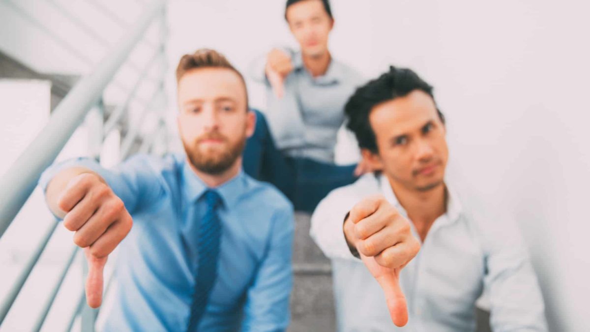 Three guys in shirts and ties give the thumbs down.