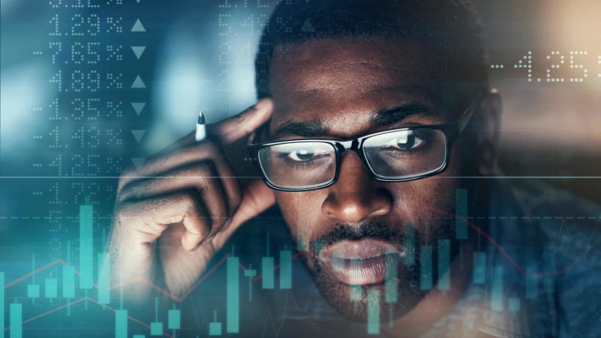 A man is deep in thought while looking at graph and rising and falling percentages.