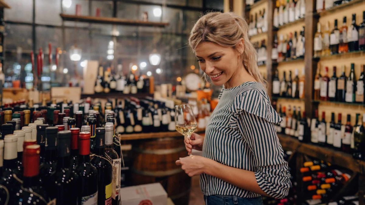 A woman wine tasting in a bottle shop.