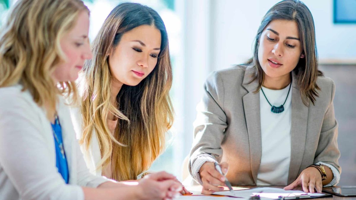 Three businesswomen collaborate around a table.