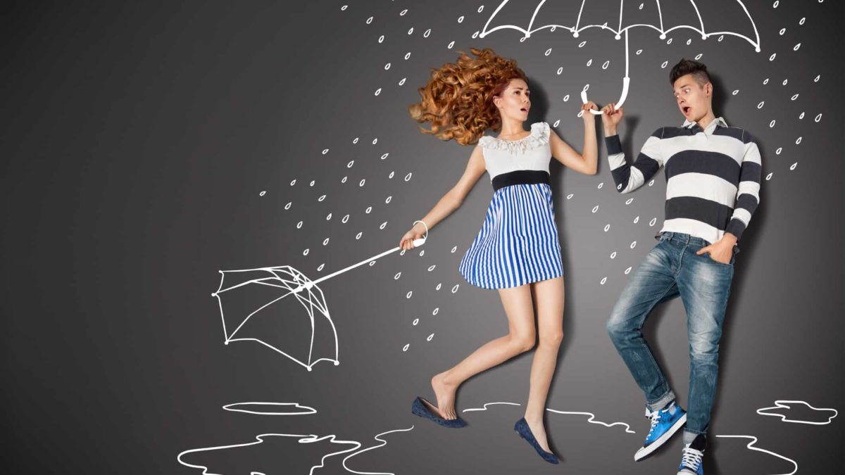 A woman steps into a friend's umbrella after hers blows away.