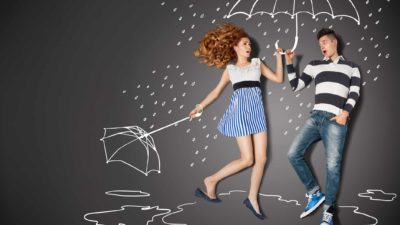 A woman steps into a friend's umbrella after hers blows away.
