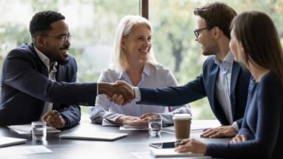 Two people shaking hands in the boardroom on a merger.