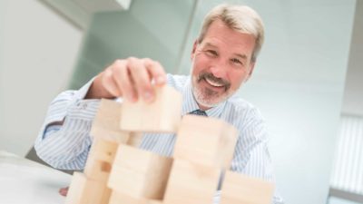 A businessman stacks building blocks.