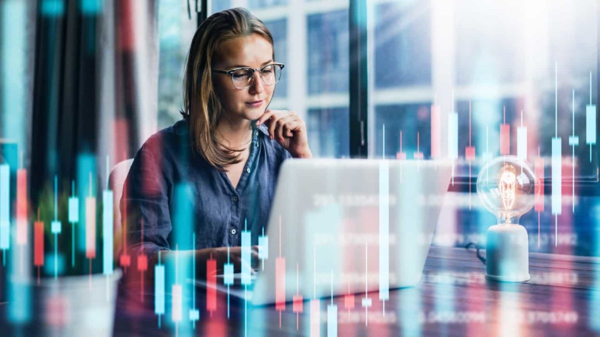 Broker looking at the share price on her laptop with green and red points in the background.