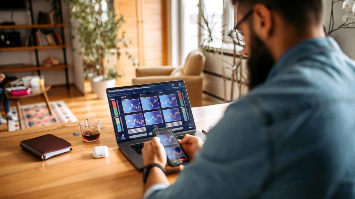 Broker checking out the share price oh his smartphone and laptop.