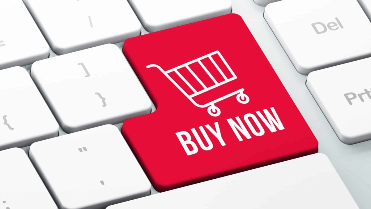 Buy now written on a red key with a shopping trolley on an Apple keyboard.