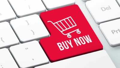 Buy now written on a red key with a shopping trolley on an Apple keyboard.