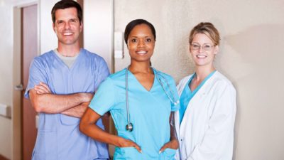 Three healthcare workers standing together and smiling.
