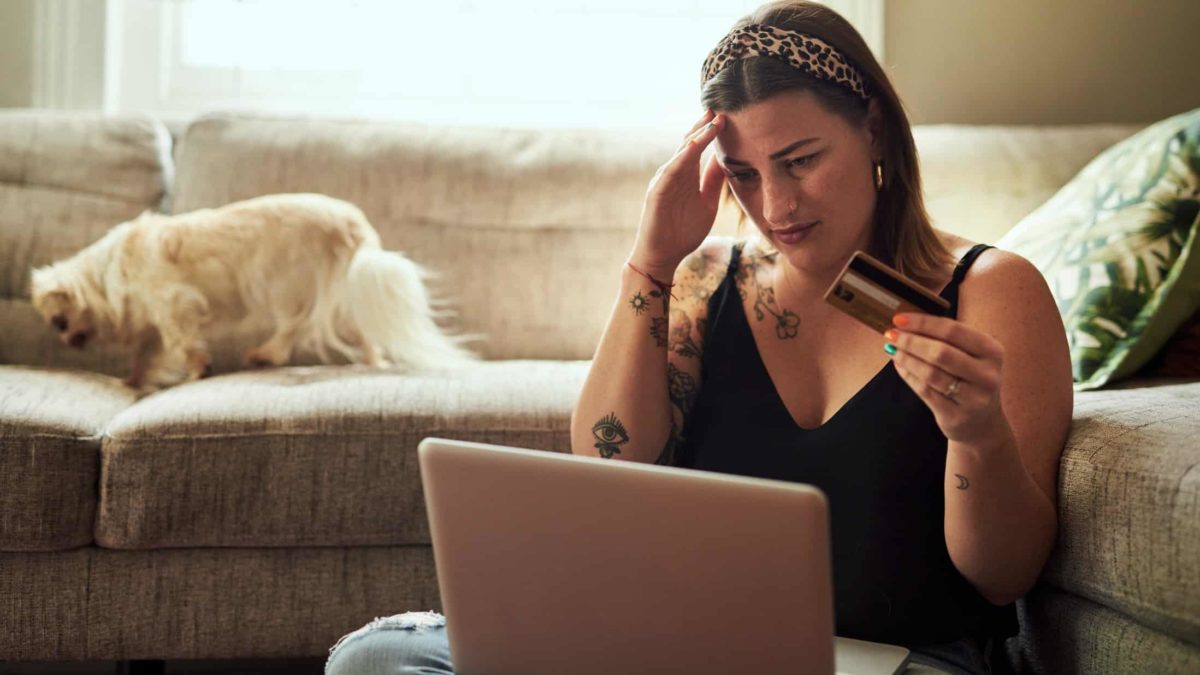Upset woman with her hand on her forehead, holding a credit card.