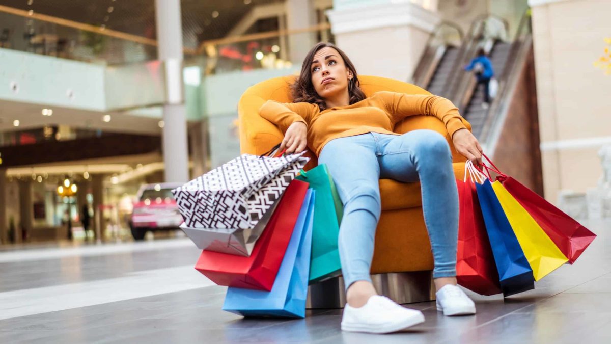 Sad shopper sitting on a sofa with shopping bags.