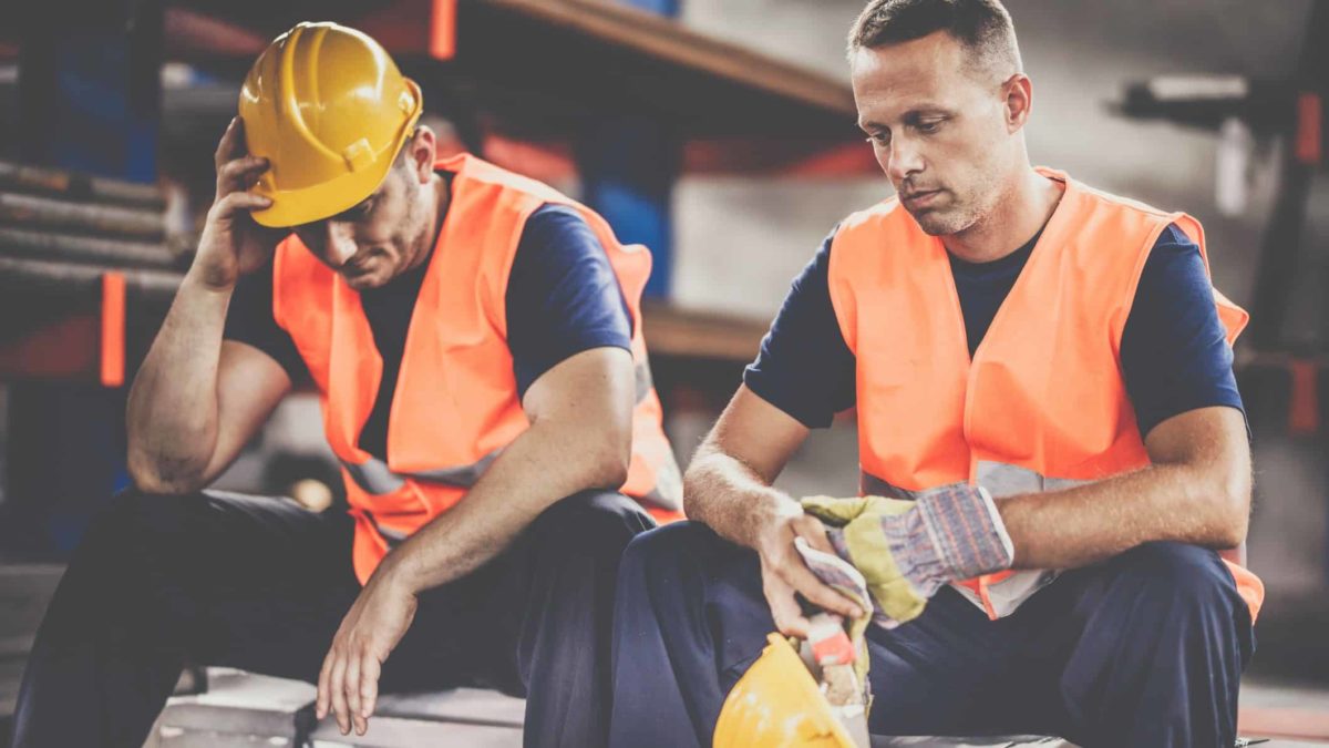 epressed manual workers on a break at a work site.