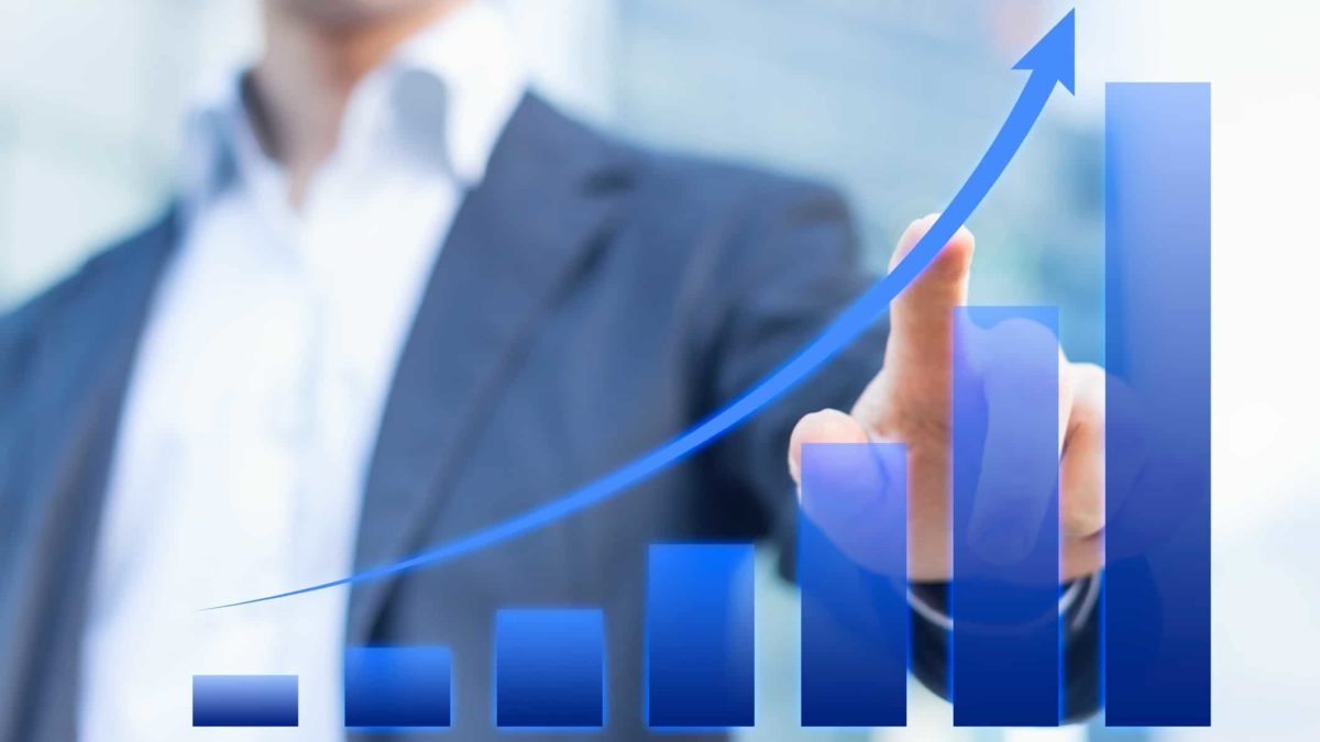 Person pointing at an increasing blue graph which represents a rising share price.