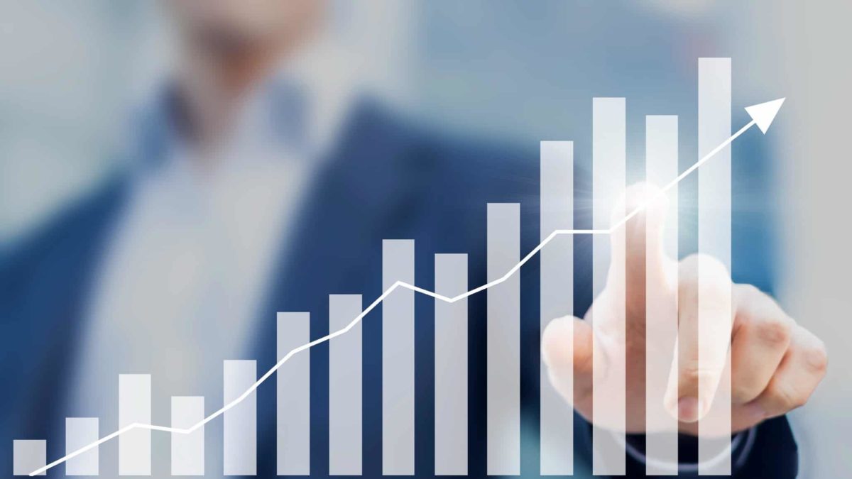 Person pointing finger on on an increasing graph which represents a rising share price.