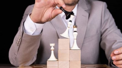 A person playing chess knocks over one of the pieces.