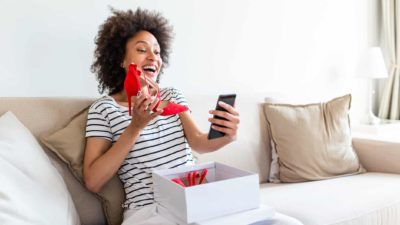 A woman shows a friend her new spiked heel shoes on a video chat.