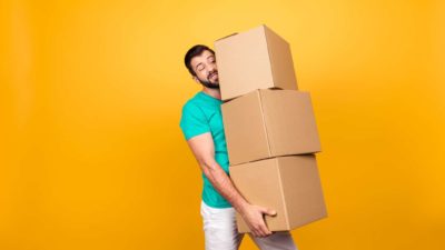 A man strains under the weight of three heavy boxes.