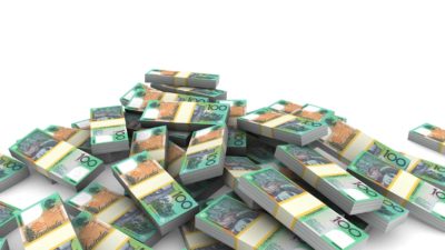 a large pile of cash made up of bundled $100 notes is piled against a plain background.