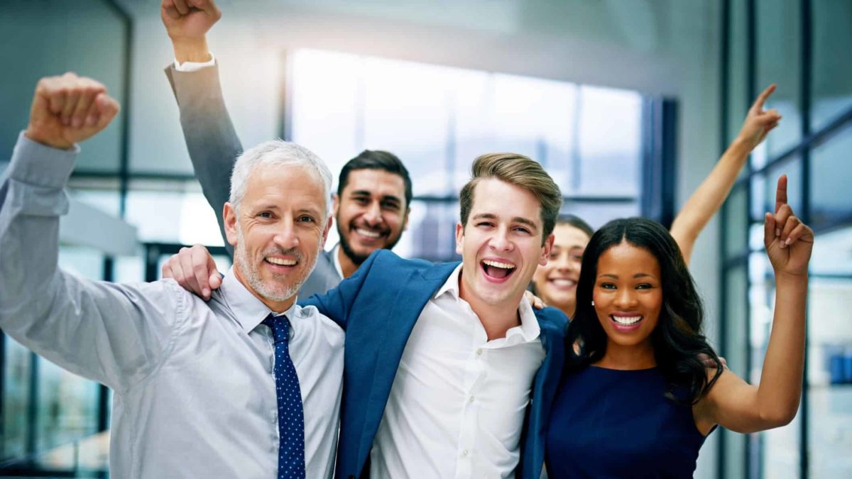 A group of business people pump the air and cheer.