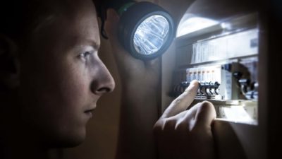 Man restores power on a circuit breaker after electricity outage.