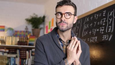 A man clasps his hands together while he looks upwards and sideways pondering how the Betashares Nasdaq 100 ETF performed in the 2022 financial year