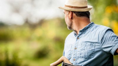 A farmer looks backwards towards his crops.