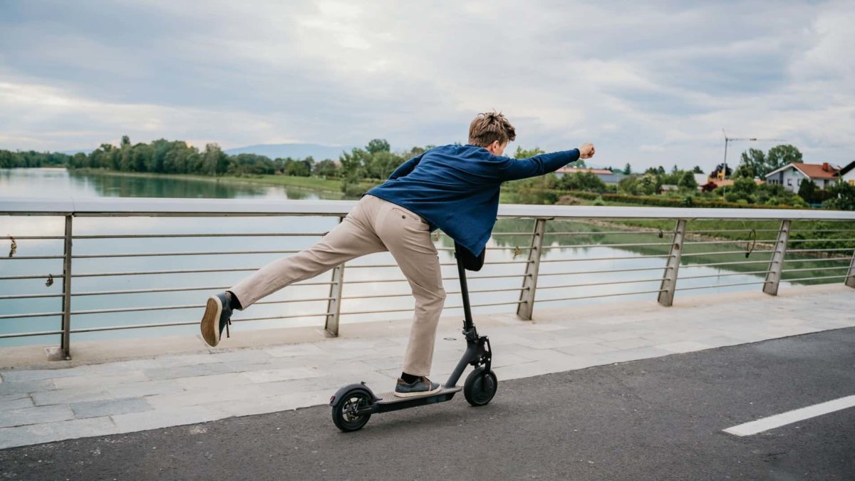 A man scoots in superman pose across a bride, excited about a future with electric vehicles.