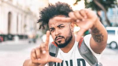 A hipster looking guy sizes up his target, making a frame with his fingers.
