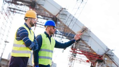 Two workers on site discuss the next stage of this civil engineering job, one points his hands upwards.