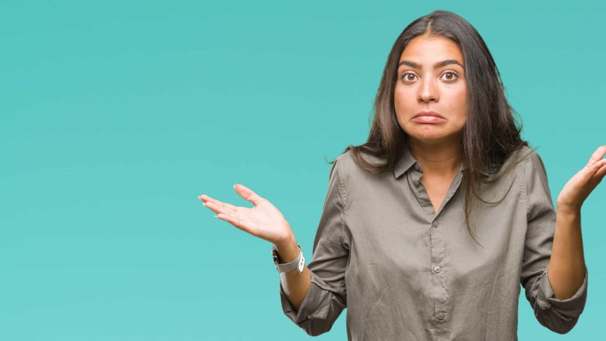 A woman shrugs and pulls awkward expression with her face.