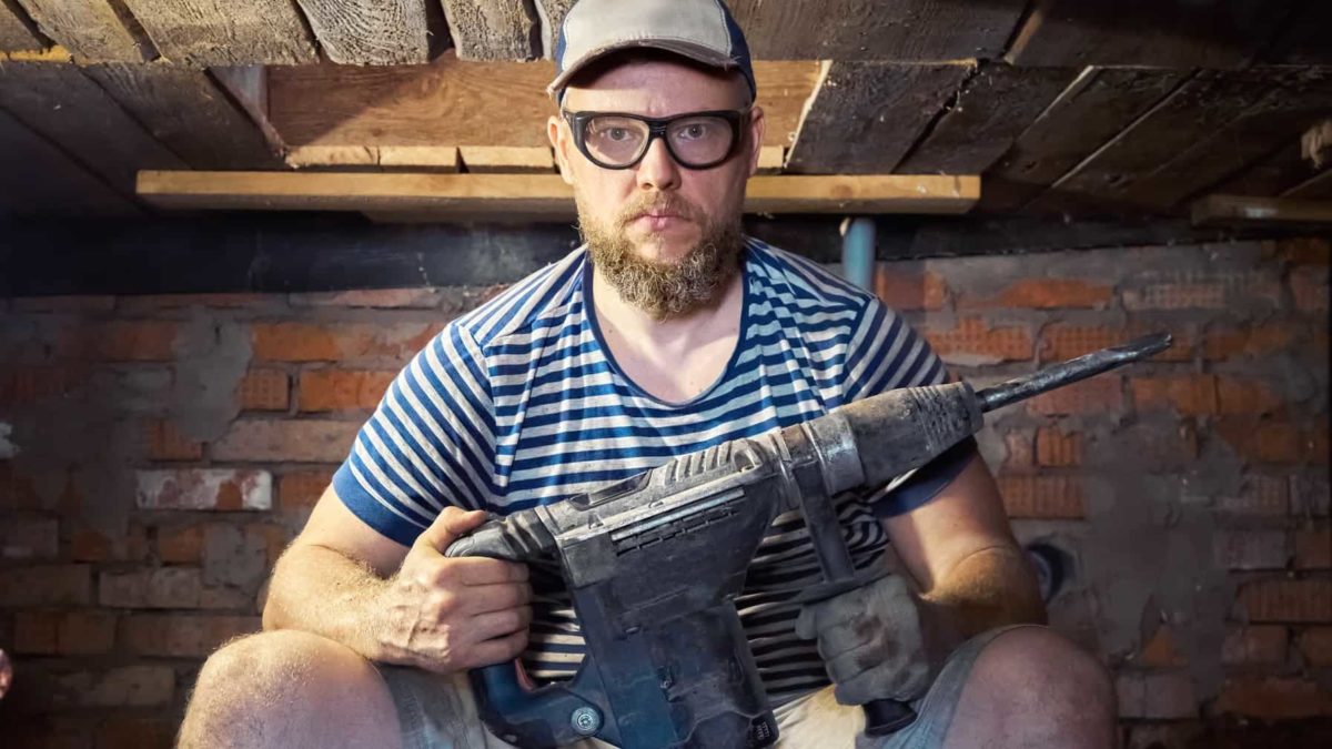 A serious construction worker ready to drill into bricks