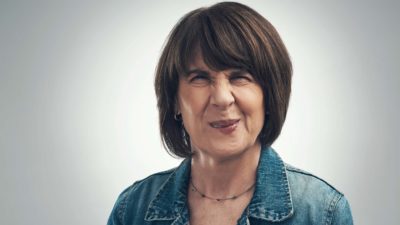 A middle aged lady screws her face up into a wince as though imaging an uncomfortable or awkward scenario.
