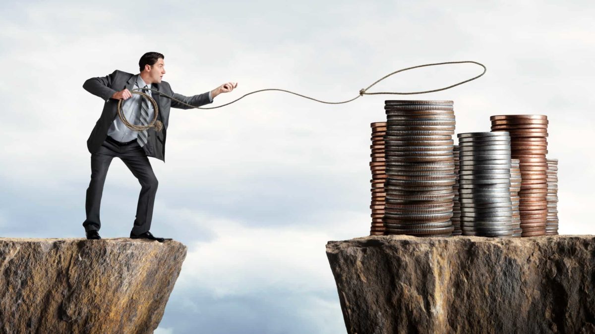 Investor trying to lasso a pile of coins across a cliff, indicatin a value trap scenario