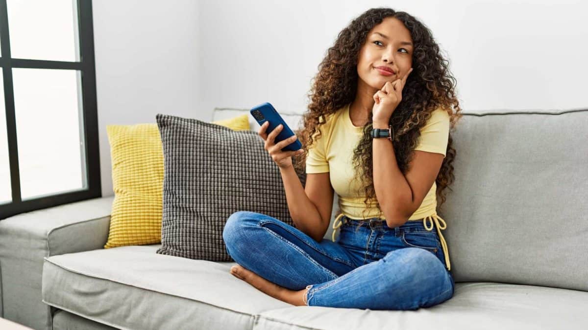 A woman sits on sofa pondering a question.