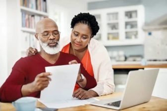 Man and woman looking over documents at computer
