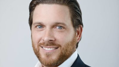 A close up head shot of Tim Carleton smiling.