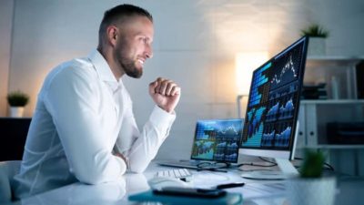 Man sits smiling at a computer showing graphs