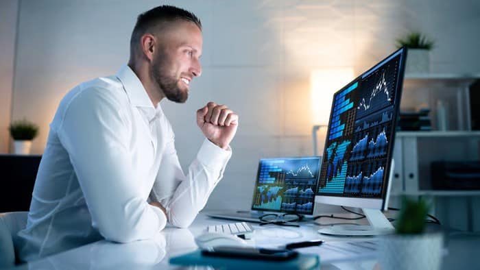 Man sits smiling at a computer showing graphs