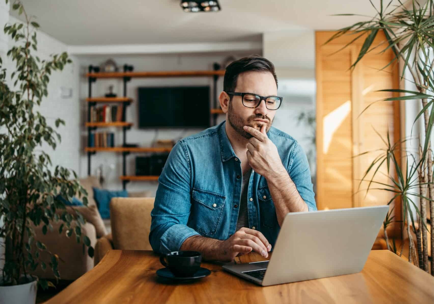 A man sitting at his dining table looks at his laptop and ponders the CSL balance sheet and the value of CSL shares today
